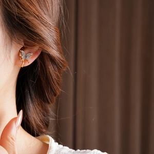 Detailed close-up of a butterfly ear cuff with 18k gold plating and blue crystals