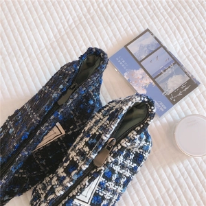 Detailed macro shot of blue tweed fabric texture on high-quality zippered makeup bags