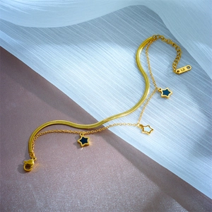 Double-layered gold chain bracelet with black and white star charms on silk fabric