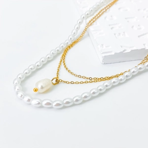 Double-layer necklace with white pearls, gold chain and baroque pearl pendant on stone