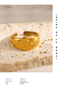 Detail of gold-plated star engraved ring resting on a minimalist white natural stone base
