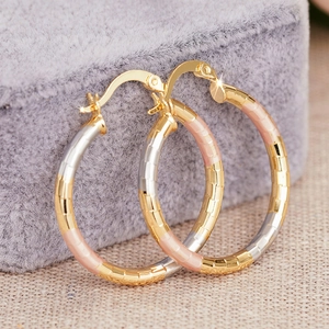 Close-up of tricolor metal hoop earrings with textured finish on velvet display