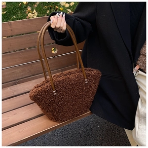 Détail de texture du sac cabas marron en peluche sur un banc en bois rustique