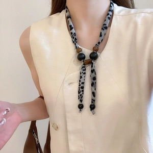 Détail du collier en tissu imprimé léopard avec perles sur le cou d'un mannequin