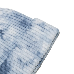 Macro detail of thick ribbed texture and blue tie-dye gradient on a knitted beanie