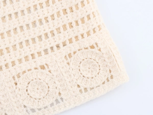 Detailed close-up of cream knit hollow mesh fabric with intricate floral crochet pattern