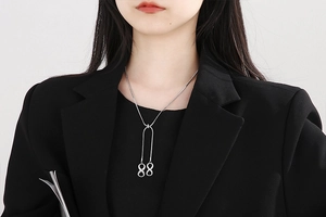 Close-up of infinity symbol pendant on a silver square snake chain worn by a model