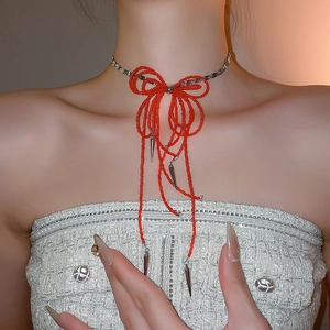 Detail of red beaded bow choker with silver metallic tassels on a model neck