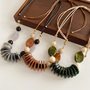 Detailed view of layered oval acrylic pendants on leather cord in three natural colors