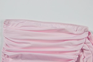 Vue détaillée de la texture du tissu froncé rose clair et des coutures de la robe