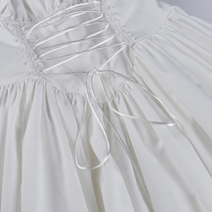 Detalle del vestido blanco con mangas abullonadas, bordes de encaje y diseño de cordones