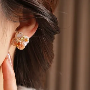 Vintage floral stud earrings with pearls and yellow crystals on model macro view