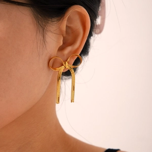 Detail of 18k gold plated stainless steel bow earrings featuring snake chain texture details