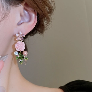 Close-up of pink flower earrings with resin petals and rhinestones worn by a model