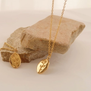 Detailed close-up of gold rose embossed oval pendants on elegant thin link chains