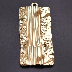 Macro shot of 18k gold plated stainless steel rectangle pendant with hammered texture