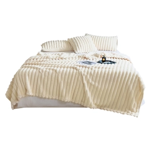 Soft creamy white rabbit fur fleece blanket with wide ribbed texture on a cozy bed