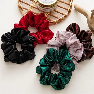 Set of five metallic pleated scrunchies in Christmas colors displayed with cozy decor