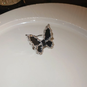Macro shot of butterfly ring with black enamel wings on a white ceramic plate