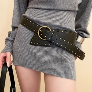 Close-up of vintage black leather belt with gold studs and large circular buckle
