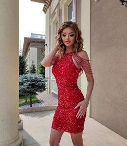 Detail of red sequin dress featuring beaded chain shoulder straps and sparkly texture