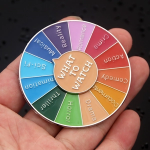 Macro shot of rotatable What to Watch enamel pin with colorful movie genre segments