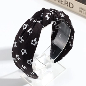 Detail shot of black fabric headband with white soccer ball print on a clear stand