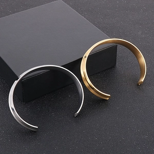 Bracciali rigidi a C in oro e argento presentati accanto a una scatola regalo nera di lusso