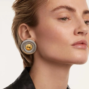 Close-up of chunky twisted gold and silver hoop earrings worn by a model for scale