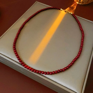 Detailed macro view of red beaded necklace with golden clasp on grey jewelry box