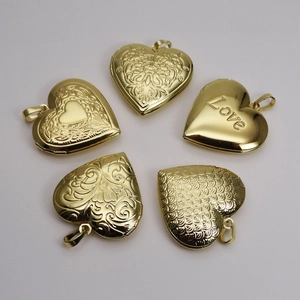 Golden heart locket pendants with intricate floral and Love engravings on gray background