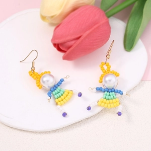 Detail of handmade beaded cartoon character earrings with white pearl and gold hooks
