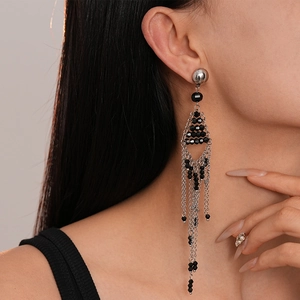 Gros plan de boucles d'oreilles à pompons en perles noires sur mannequin, style vintage sombre