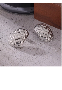 Macro detail of silver geometric quilted pattern on polished stainless steel stud earrings
