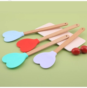 Close-up of heart-shaped silicone spatulas in four colors with natural beech wood handles
