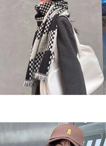 Detail of a black and white checkered plaid scarf with tassels and a brown bear baseball cap