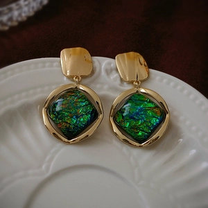 Macro detail van vintage geometrische oorbellen met groene harsinleg en goud metaal