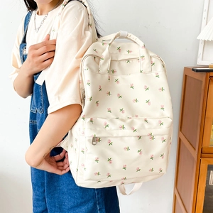 Close-up of a floral print backpack in beige with pink flowers on a female model