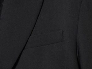 Close-up of the black blazer fabric texture showing lapel and pocket stitching details