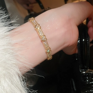 Close-up of a luxurious gold heart-shaped bracelet with pave-set zircons on a model