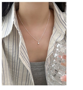 Close-up of minimalist silver heart pendant necklace worn on a striped shirt