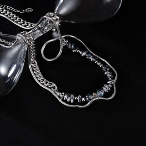 Detail of double-layer stainless steel Cuban chain with dark natural stones on glass