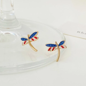 Macro view of gold dragonfly earrings with red, white, and blue enamel details