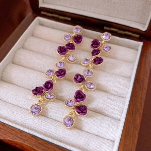 Detailed macro view of purple rose drop earrings with crystals in a jewelry box