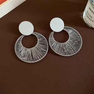 Detailed view of silver wire-wrapped geometric hoop earrings on a textured background