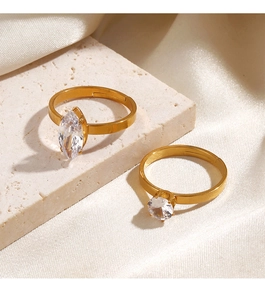 Detail of two gold open rings with marquise and round zircon stones on stone and silk