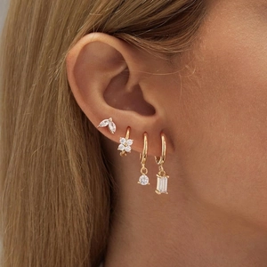Detailed view of 18K gold earrings set with white zircons worn on ear in lifestyle lighting