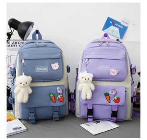 Detail view of light blue and purple canvas backpacks with cartoon patches and bear pendant