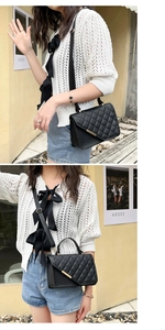 Detail of black quilted shoulder bag with gold metal trim and wide textile strap
