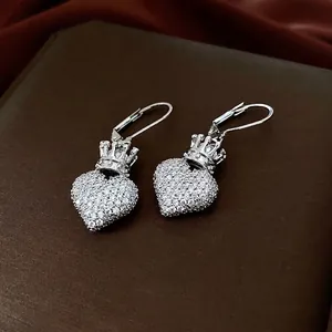 Boucles d'oreilles cœur couronne avec zircons étincelants sur fond en satin rouge